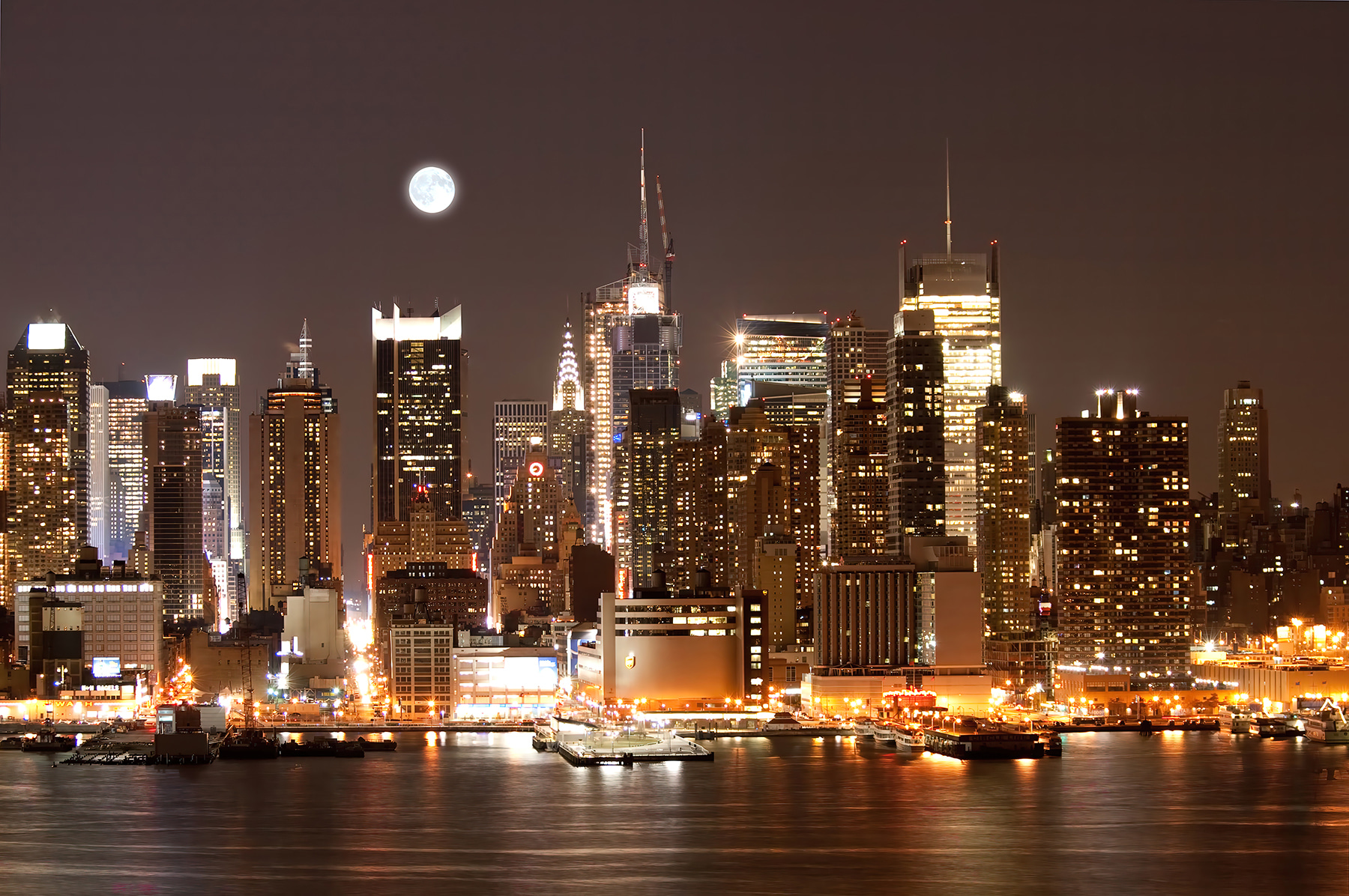 City skyline at night with the moon in the sky