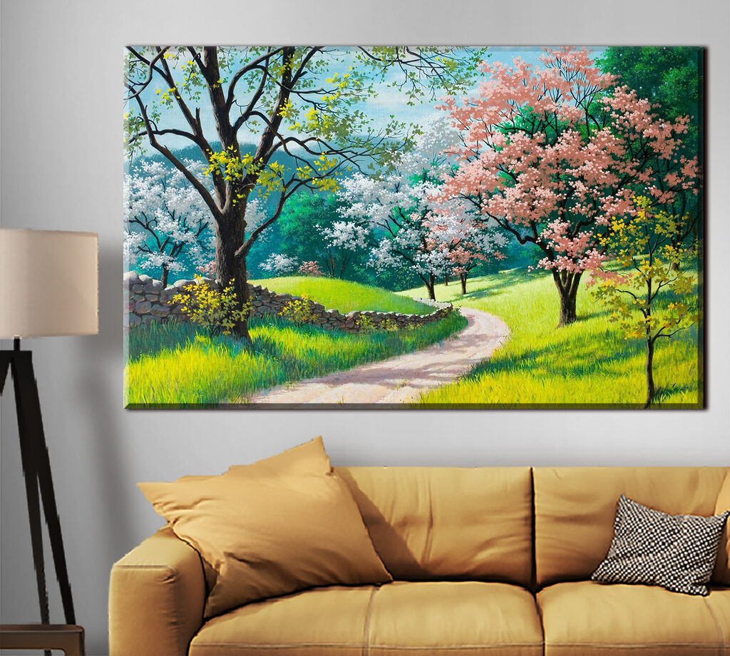 A dirt road through a grassy field with trees and a stone wall