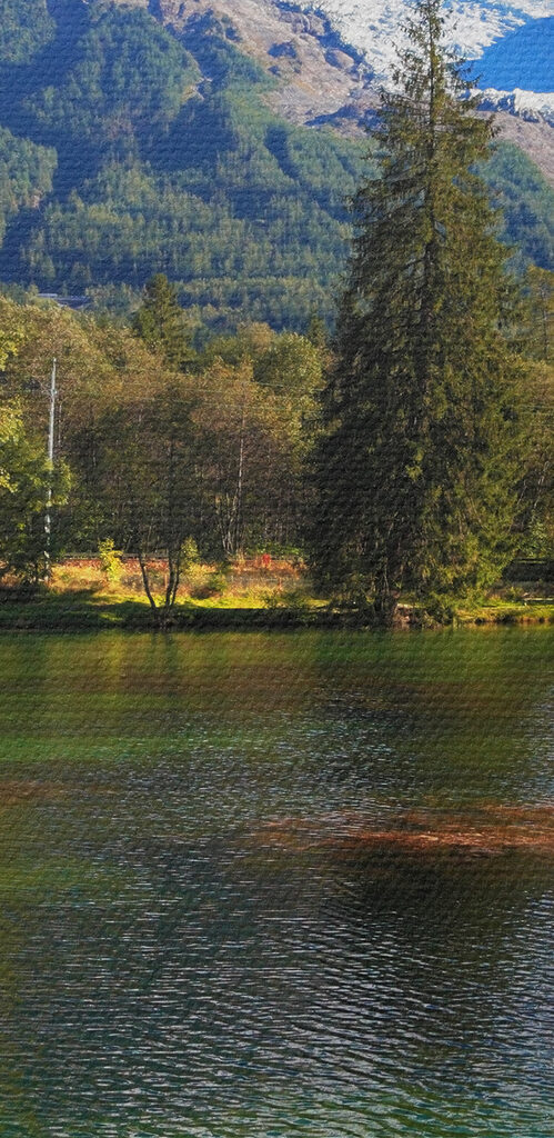 A lake surrounded by trees and mountains A lake surrounded by trees and mountains