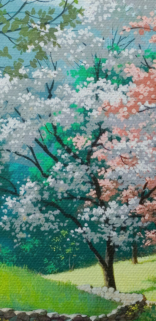 A dirt road through a grassy field with trees and a stone wall