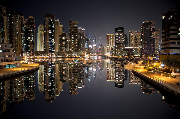 City skyline with lights reflecting on water City skyline with lights reflecting on water
